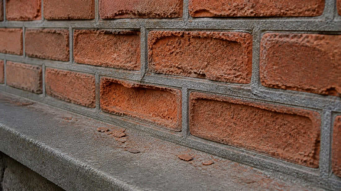 Old soft handmade brick wall where the brick faces have eroded and hollowed back while weathered gray cement repointing joints stand proud and intact above a stone ledge